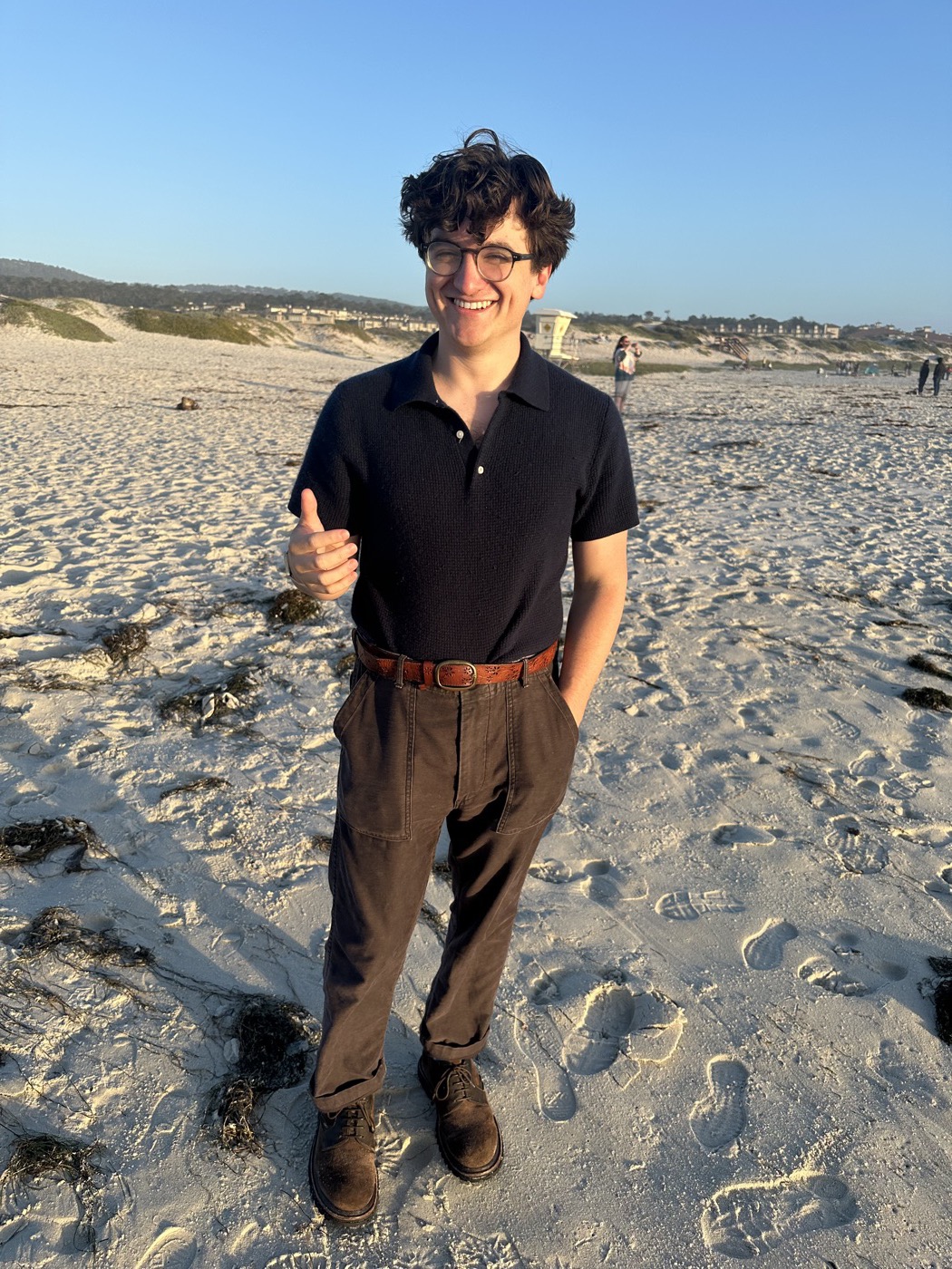 Thomas Costello on a beach, giving a thumbs up